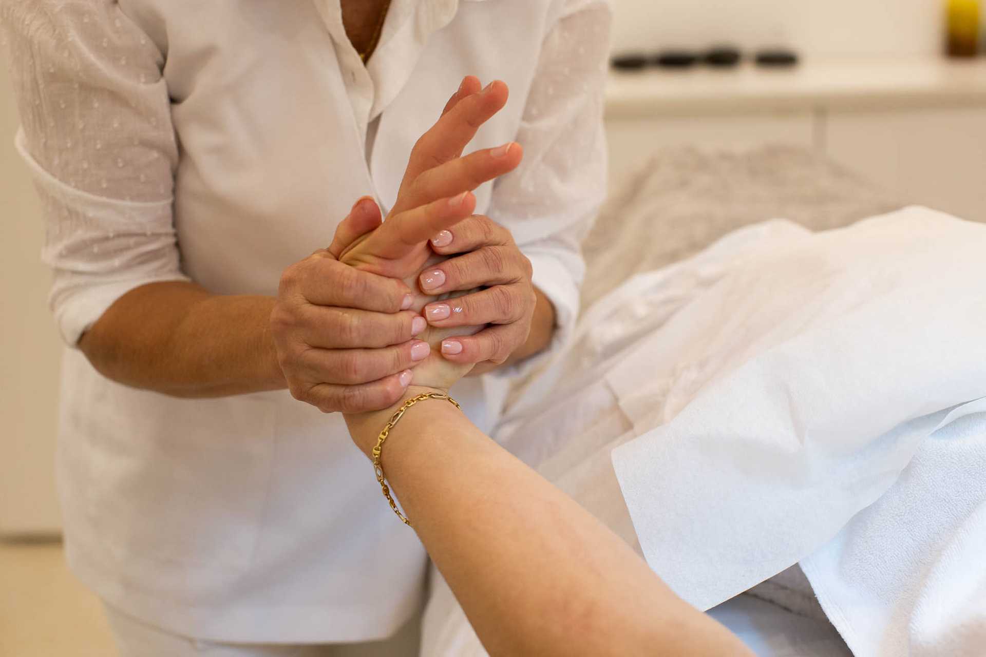 Therapist performing a gentle hand massage on a client's wrist.