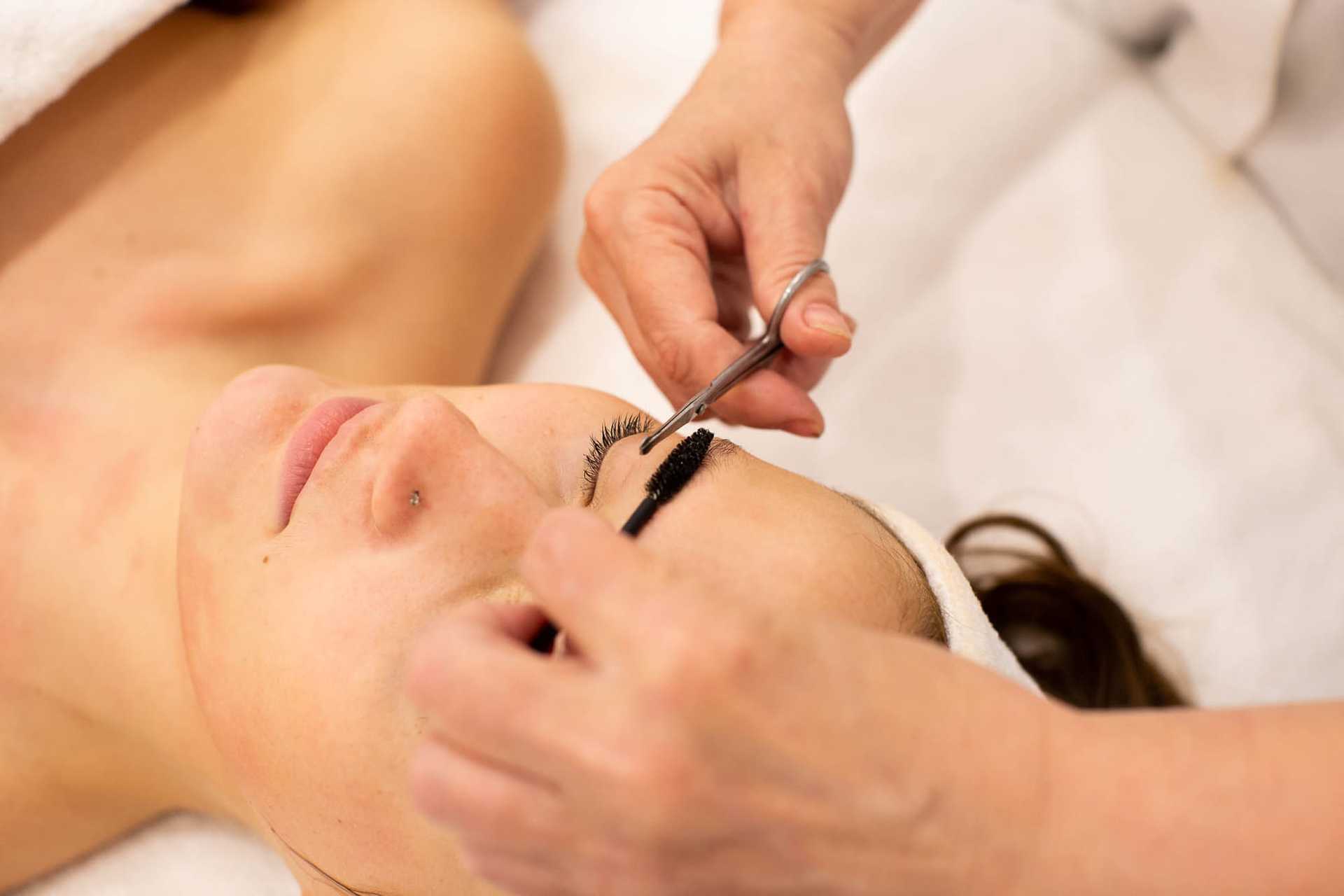 Woman receiving an eyelash tinting service in a spa setting.
