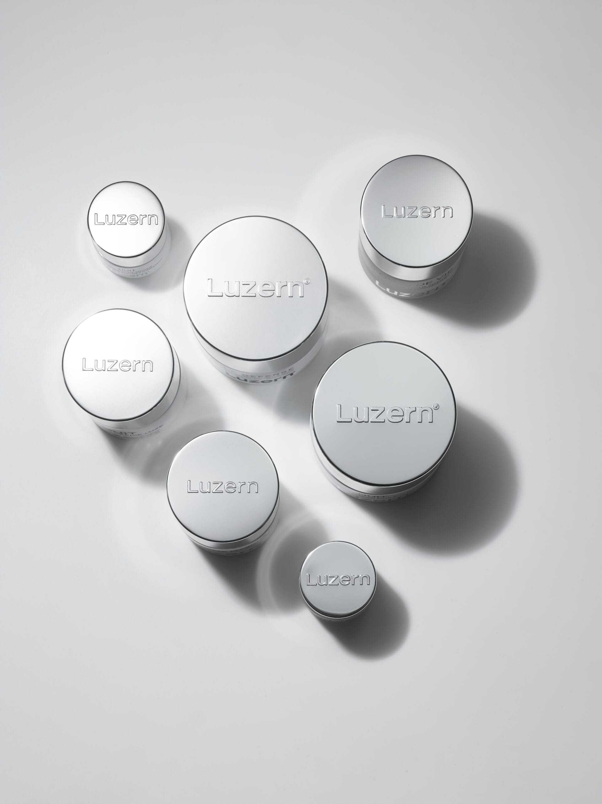 Luzern skincare containers arranged on a smooth, white surface.
