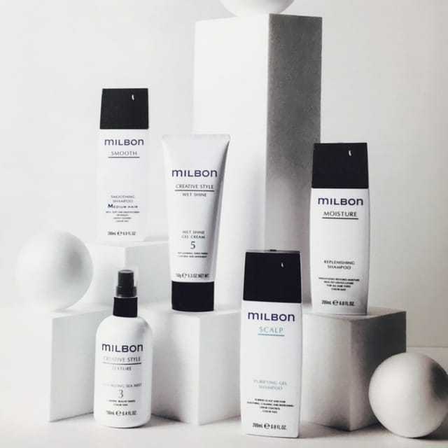 Milbon hair products displayed on geometric white shapes, featuring various styling and care items.