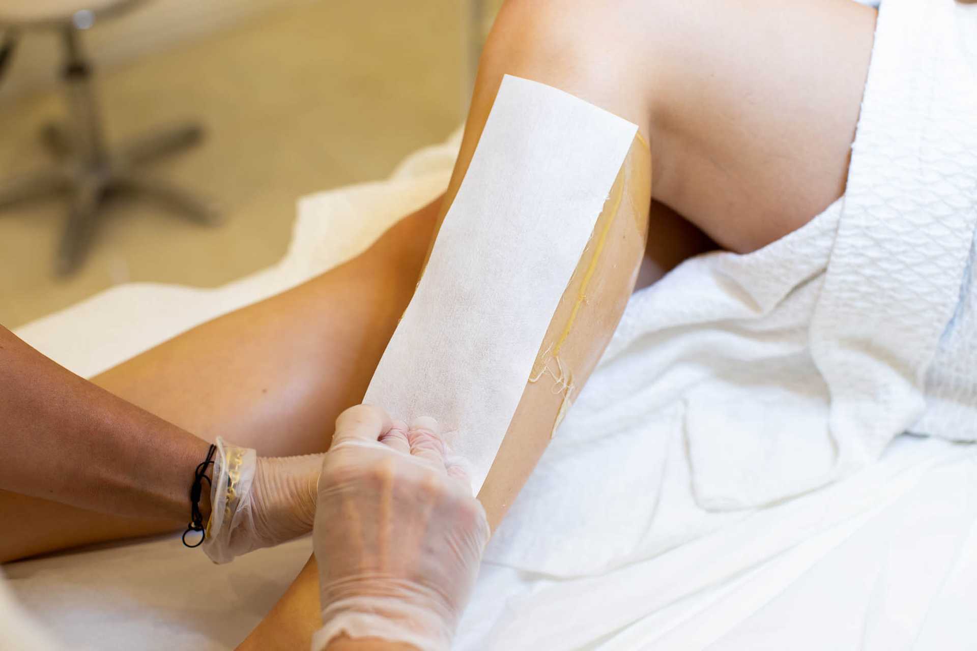Person receiving a leg waxing treatment at a spa or salon.